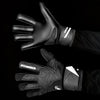 A close-up of black latex goalkeeper gloves with a wrist strap shown on a hand.