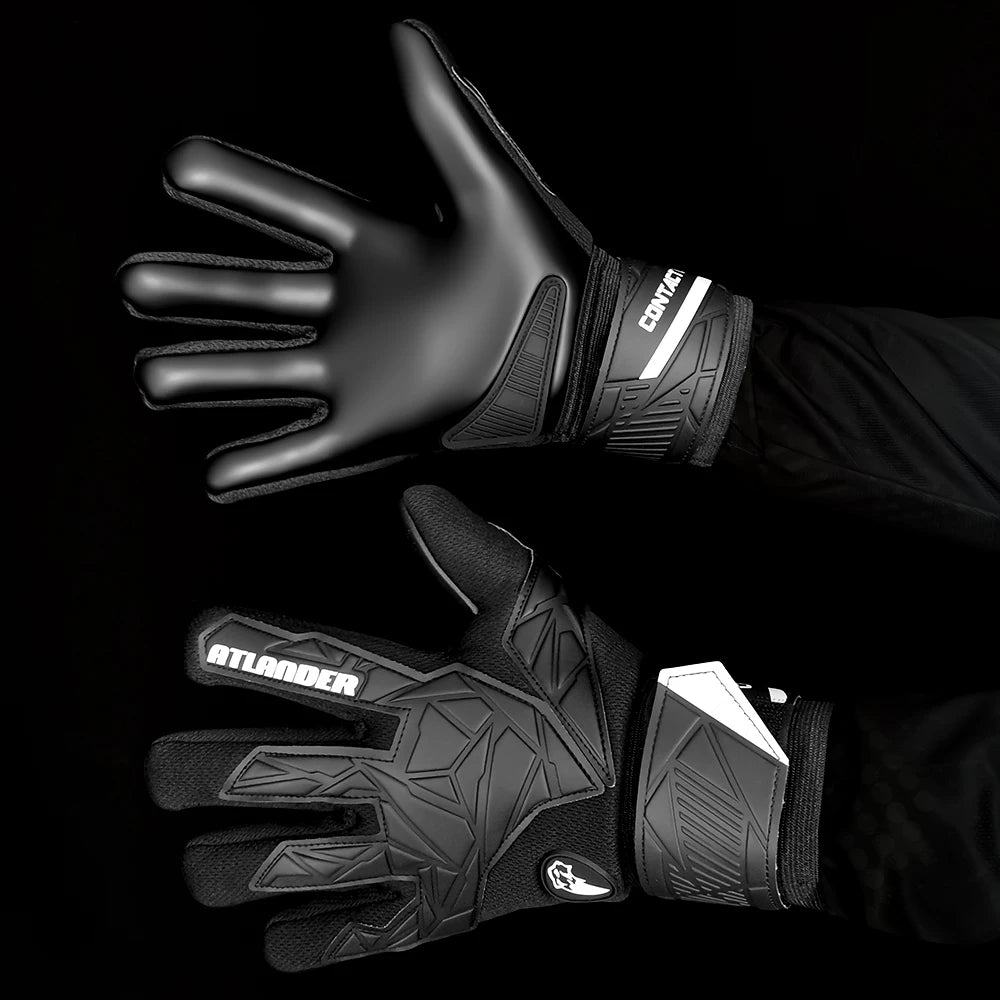 A close-up of black latex goalkeeper gloves with a wrist strap shown on a hand.