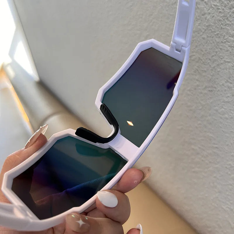 A hand holds a white UV400 cycling sunglasses case with a tinted lens against a light background.