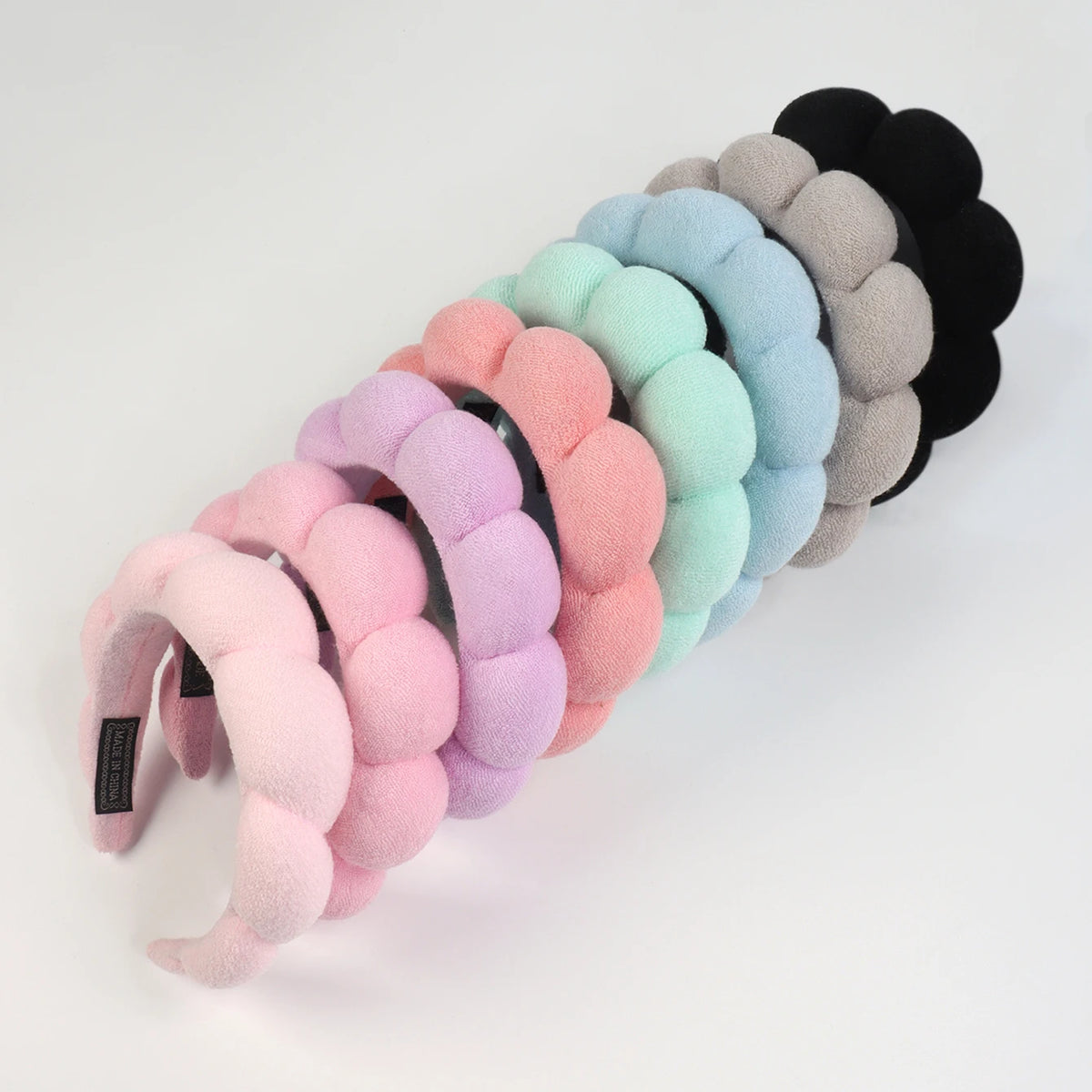 A set of colorful microfiber skincare headbands and wristbands in pastel shades and black.