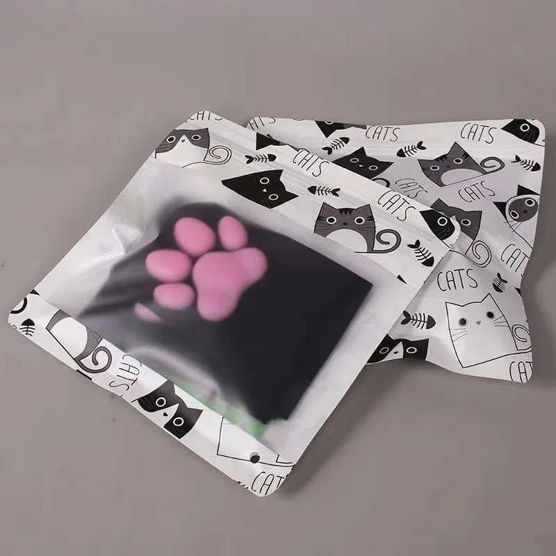 A pair of black thigh-high socks featuring a repeating cat motif and a pink paw print design.