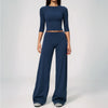 A woman wearing a navy blue yoga and fitness leggings set consisting of a long-sleeved top and matching pants.