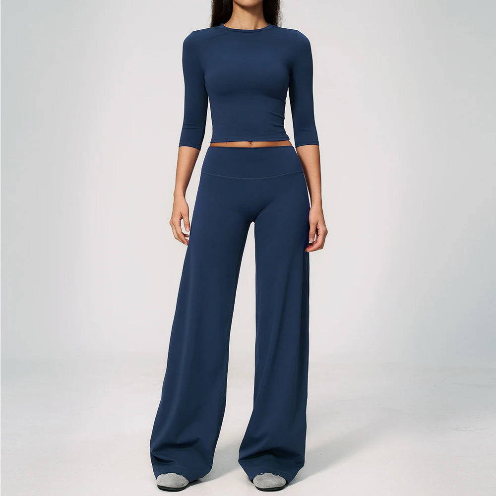 A woman wearing a navy blue yoga and fitness leggings set consisting of a long-sleeved top and matching pants.