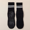 Pair of black grip socks with white stripes and a textured sole for yoga and barre