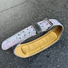 A light pink and white patterned leather weightlifting belt with a black buckle resting on a dark surface.
