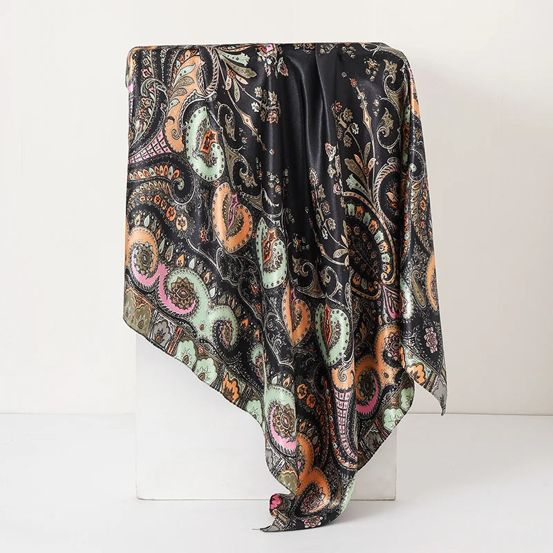 A black silk paisley shawl draped on a white surface.