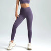 A model wearing seamless high-waist yoga leggings in purple and a matching cropped top, standing and looking down.