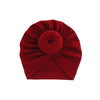 Tiefrote, solide Baumwoll-Baby-Turban-Kopftuch in Rosettenform gefaltet.