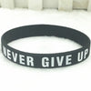 Bracelet silicone noir avec le texte NEVER GIVE UP sur une surface blanche et duveteuse.