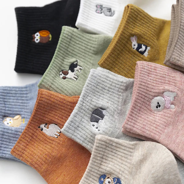 A collection of embroidered cotton socks in various colors and patterns, including black, green, yellow, pink, and gray.