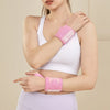 A woman wearing a pink wrist guard bandage on her arm while exercising.