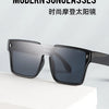 A pair of modern, dark gray sunglasses resting on a white surface.