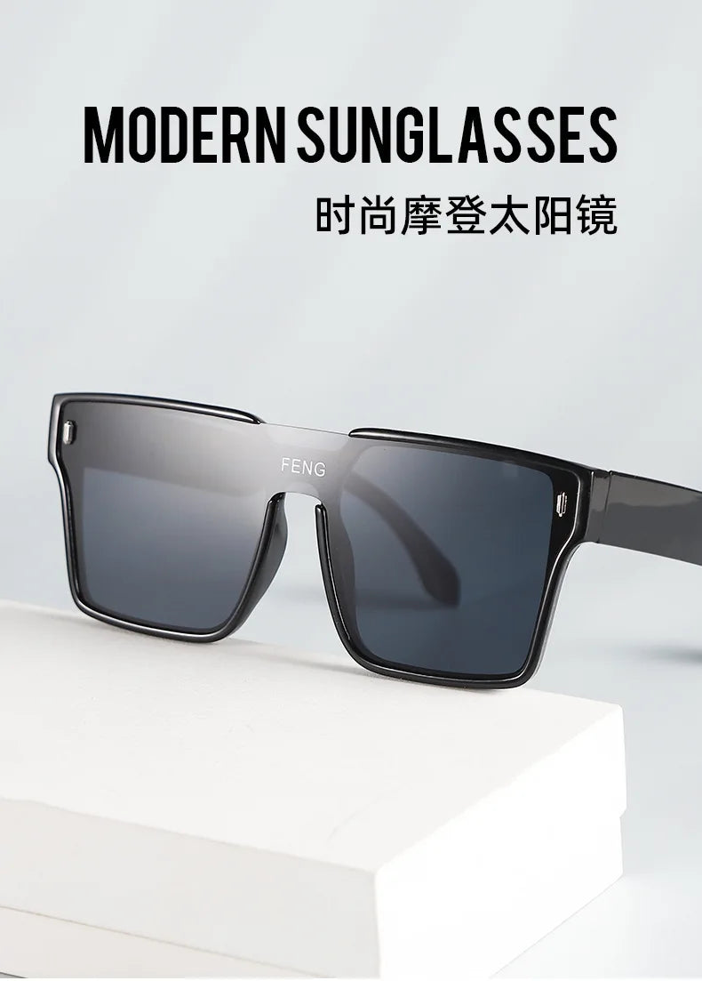 A pair of modern, dark gray sunglasses resting on a white surface.