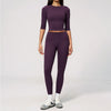 A woman wearing a matching purple yoga and fitness leggings set, consisting of a long-sleeved top and full-length pants.