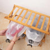 A person is holding a pink reusable drawstring storage bag over a wooden bamboo rack.