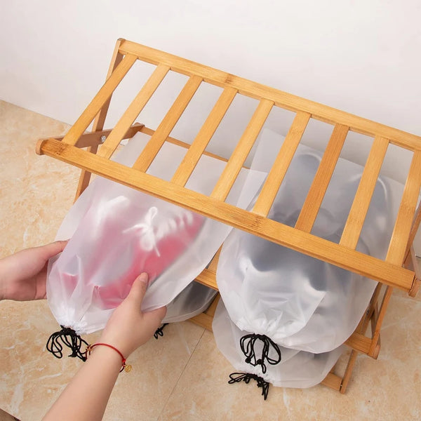 A person is holding a pink reusable drawstring storage bag over a wooden bamboo rack.