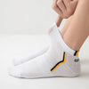 White mesh ankle socks with yellow accents shown on a person's foot.