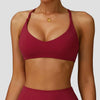 A model wearing a maroon high-support sports bra for yoga and fitness.
