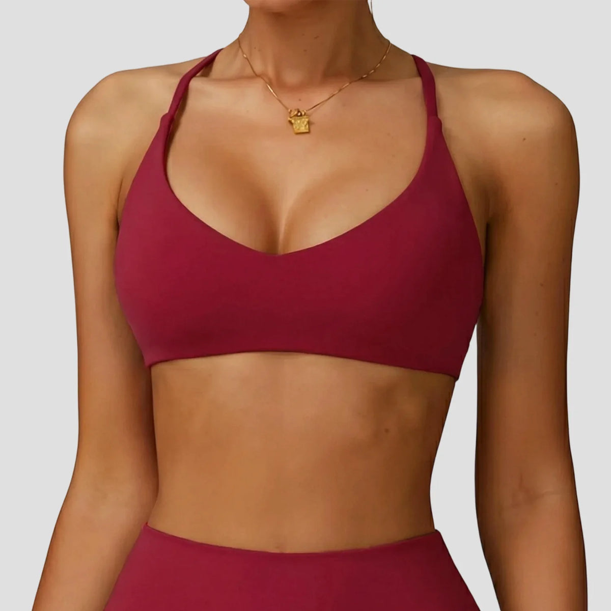 A model wearing a maroon high-support sports bra for yoga and fitness.