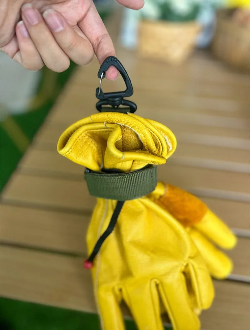 A yellow tactical nylon glove with a black hook attached, being held by a hand.