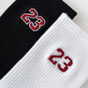 Black and white crew socks featuring a red embroidered number 23 on the cuff.