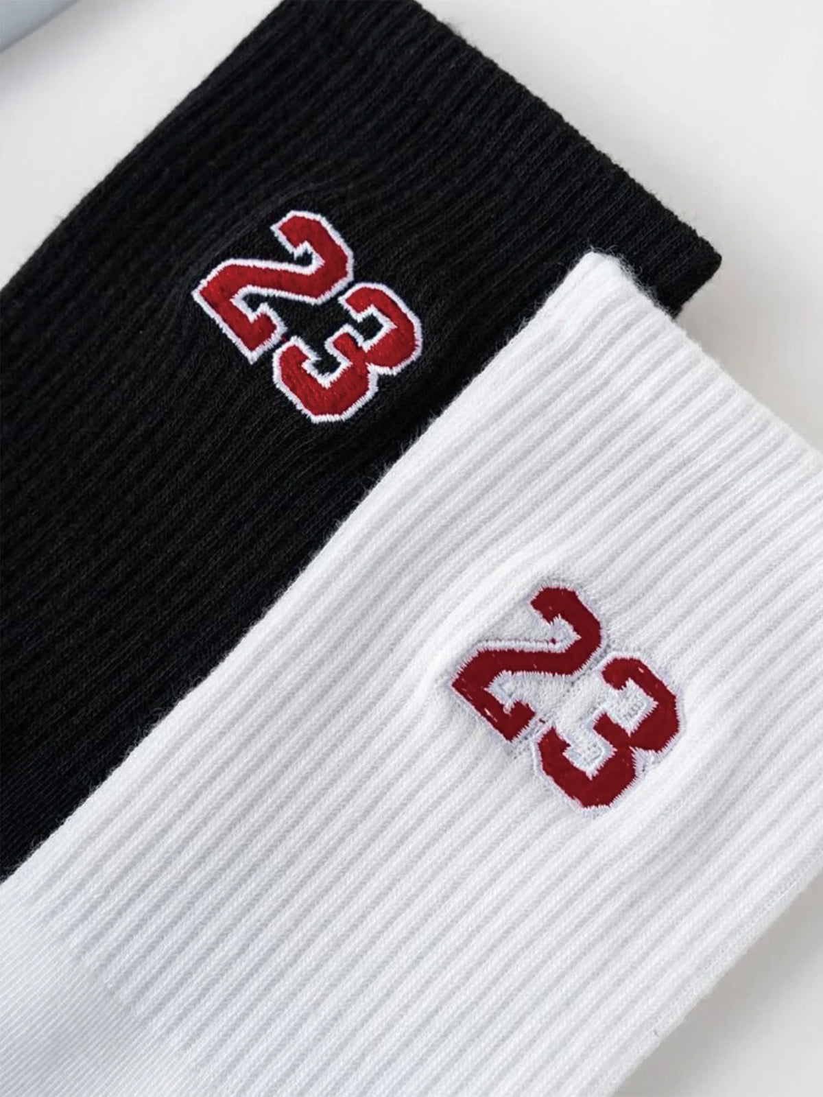 Black and white crew socks featuring a red embroidered number 23 on the cuff.