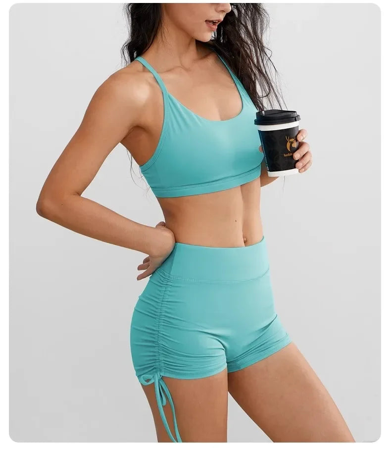 A woman models a teal performance yoga and workout shorts top and bottom set.