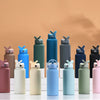 A collection of various colored stainless steel vacuum flasks or water bottles with straws arranged on a white surface.