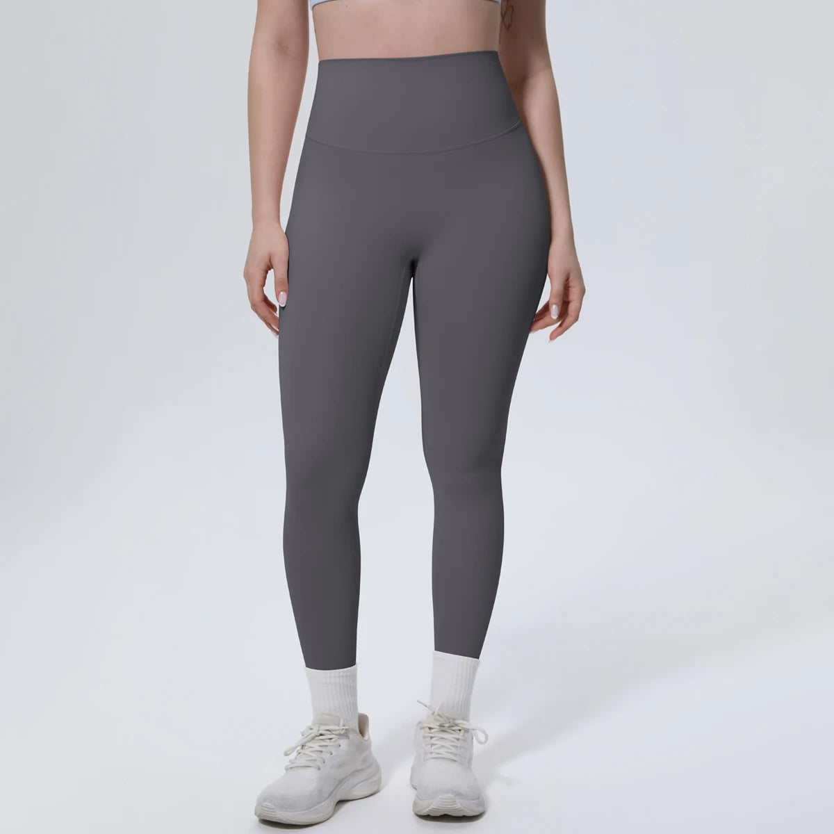 A model wearing high-waisted gray quick-drying yoga and fitness leggings and white sneakers.