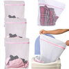Un juego de bolsas organizadoras de ropa de malla duraderas en tela rosa y blanca, algunas llenas de ropa.