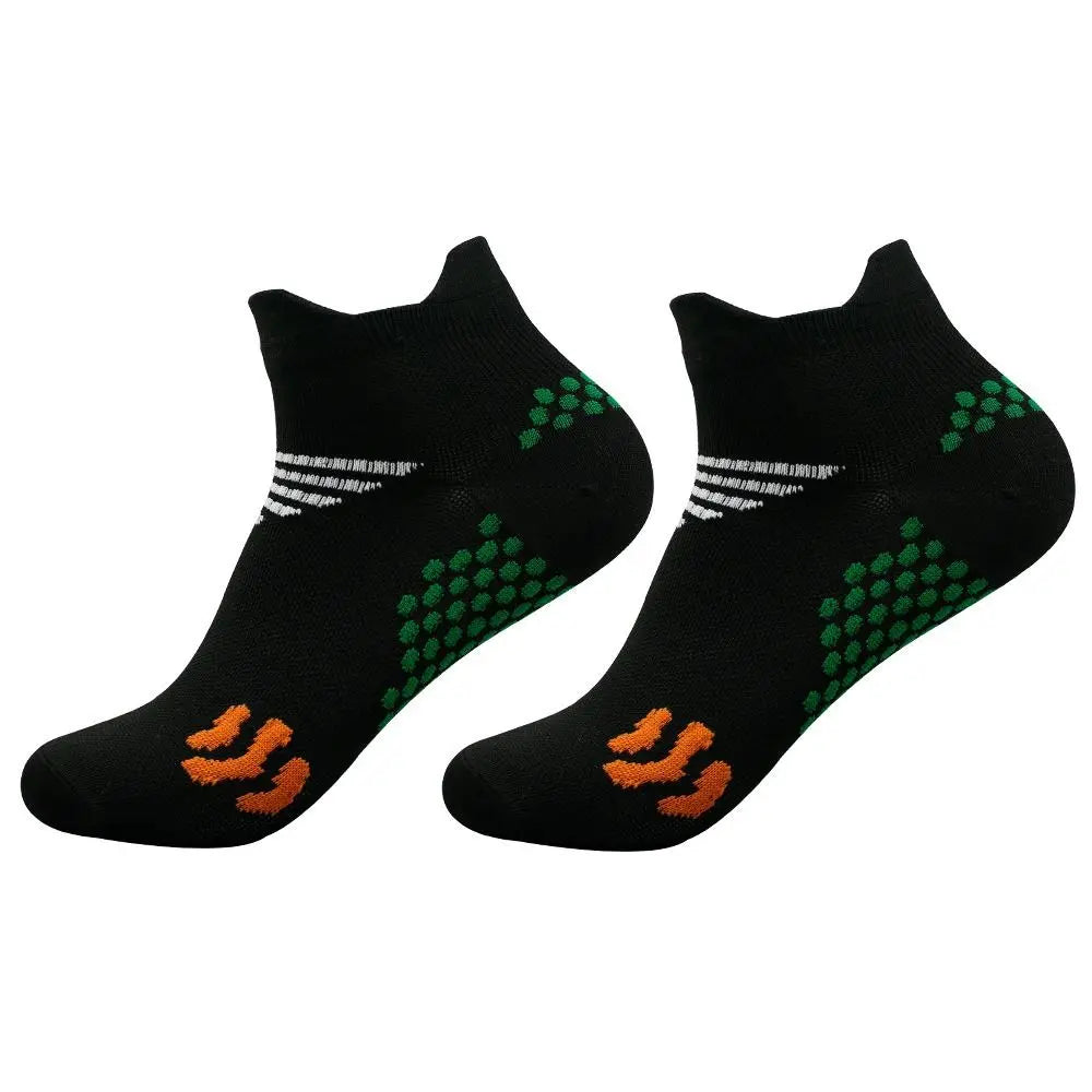 A pair of black cycling and running socks with green and orange patterned designs.