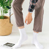 Vue de dos d'une personne portant un pantalon marron et une chemise à carreaux, avec des chaussettes blanches de type crew.