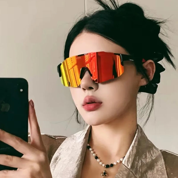 A woman wearing orange-tinted sport cycling and skiing goggles against a light background.