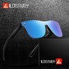 A pair of blue-tinted frameless sports sunglasses resting on a black surface next to its packaging.