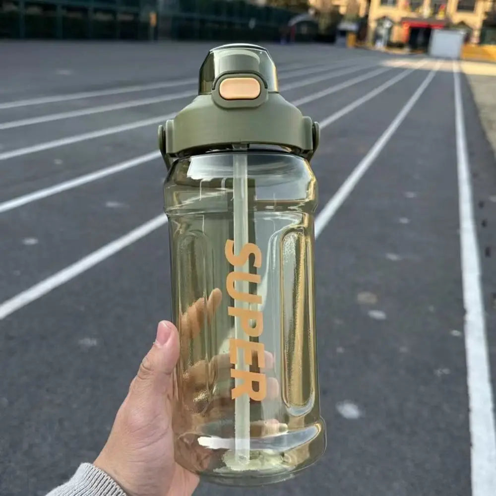 A hand holds a clear insulated sports water bottle with a metallic cap against an asphalt background.