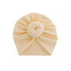 Heller beiger Baumwoll-Baby-Turban, gefaltet in Form einer Blüte.