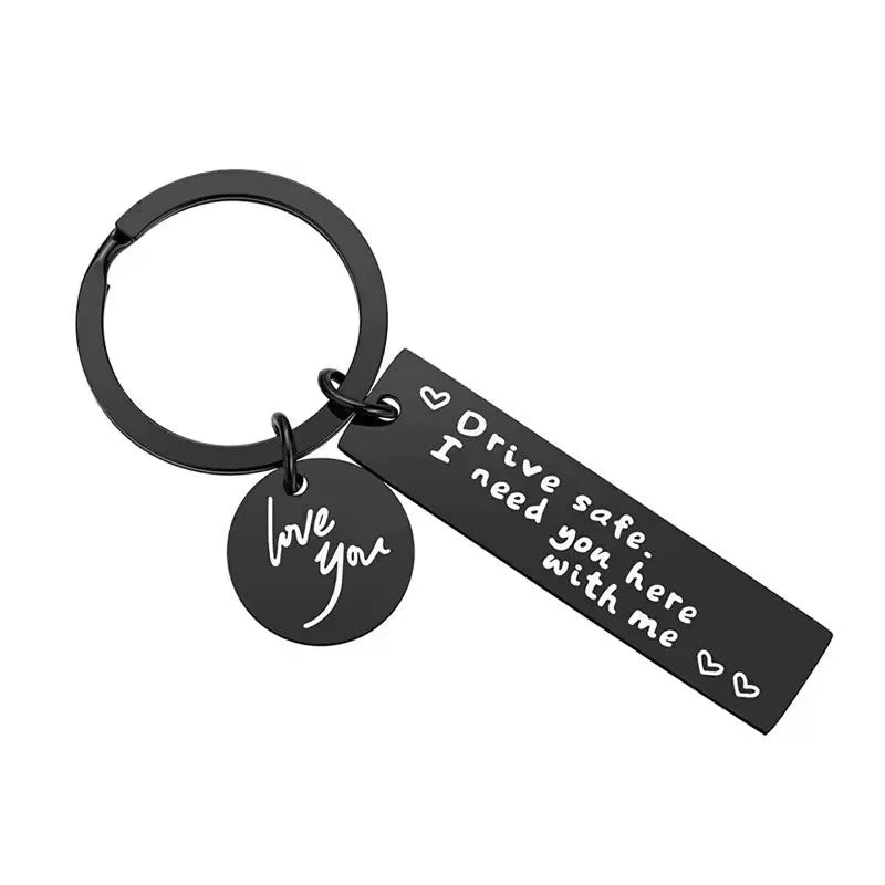 A black metal keychain with a circular ring and a tag engraved with the words I love you and Drive safe I need you here with 