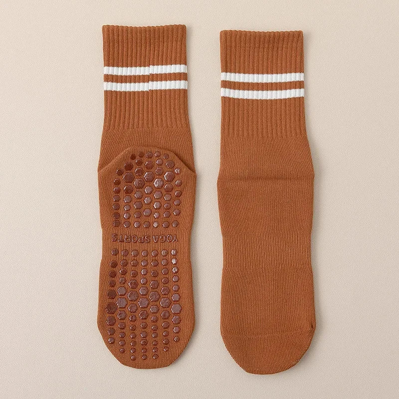 A pair of brown non-slip yoga socks with white stripes and textured soles.