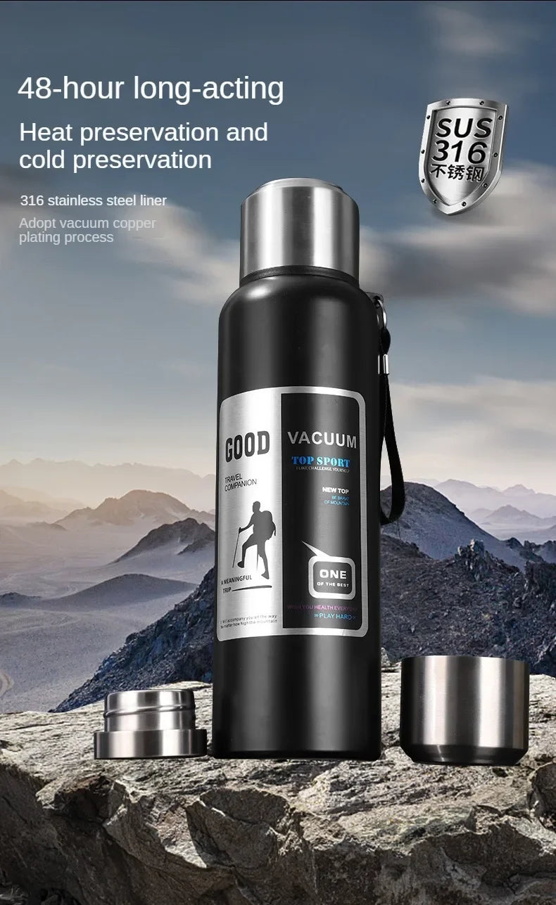 Botella térmica negra aislada con revestimiento de acero inoxidable sobre una superficie rocosa al aire libre.