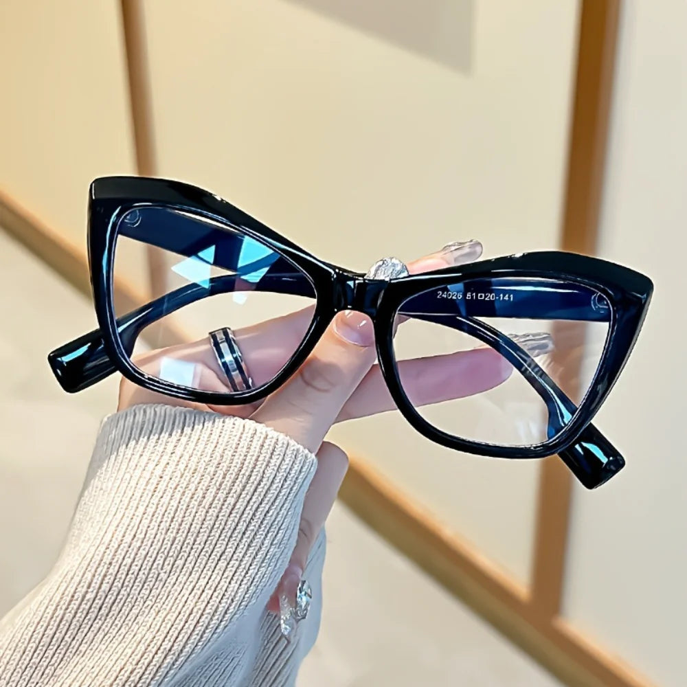 A close-up of a pair of black vintage color block blue light blocking eyeglasses being held by a person.