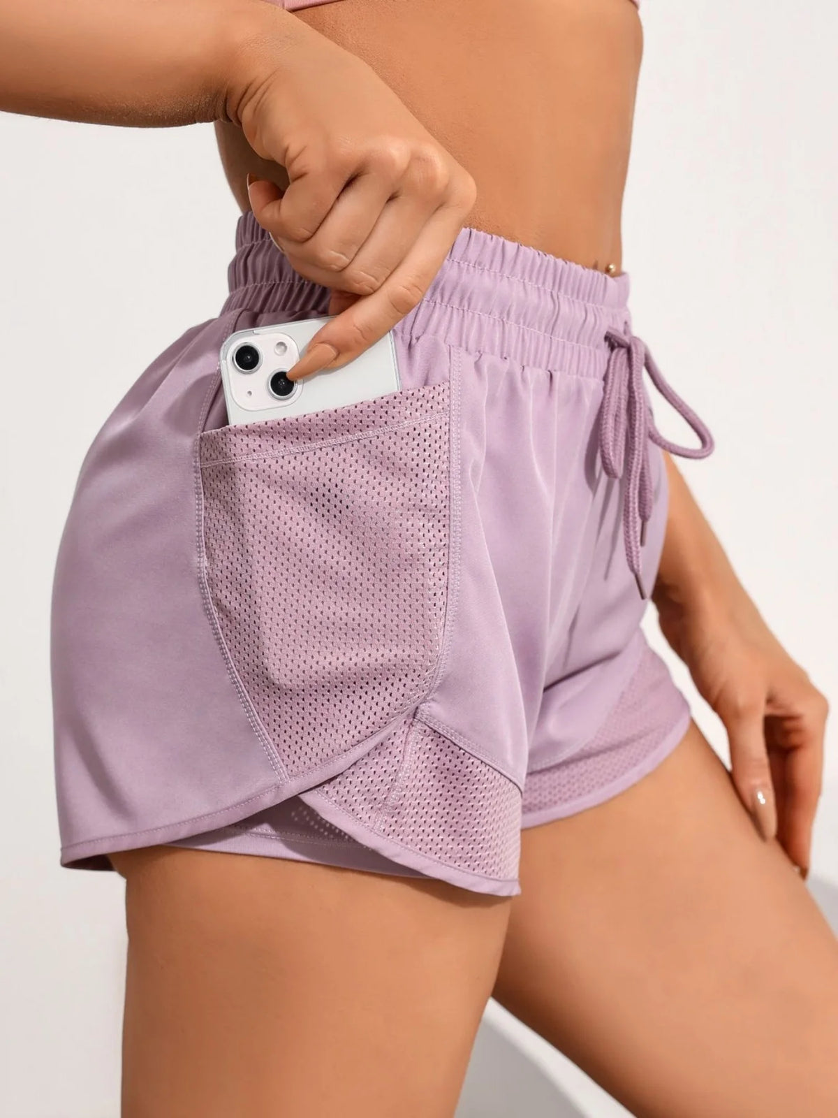 A close-up of a purple athletic short featuring mesh pockets and drawstring details.