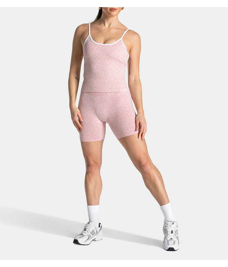 A woman models pink leopard print seamless yoga shorts and white socks.