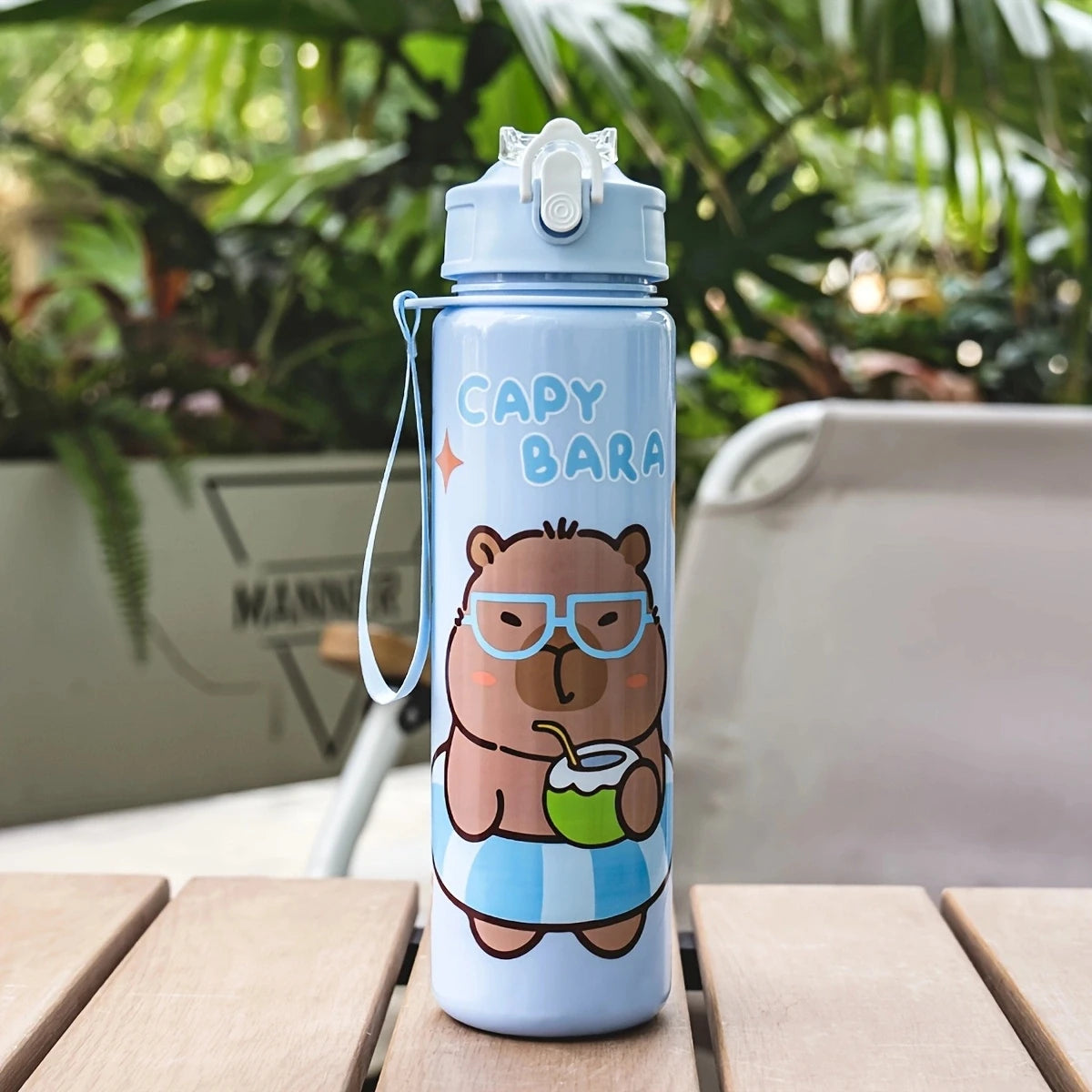 A light blue cartoon drinking water bottle with a bear face design and straw, sitting on a wooden surface.