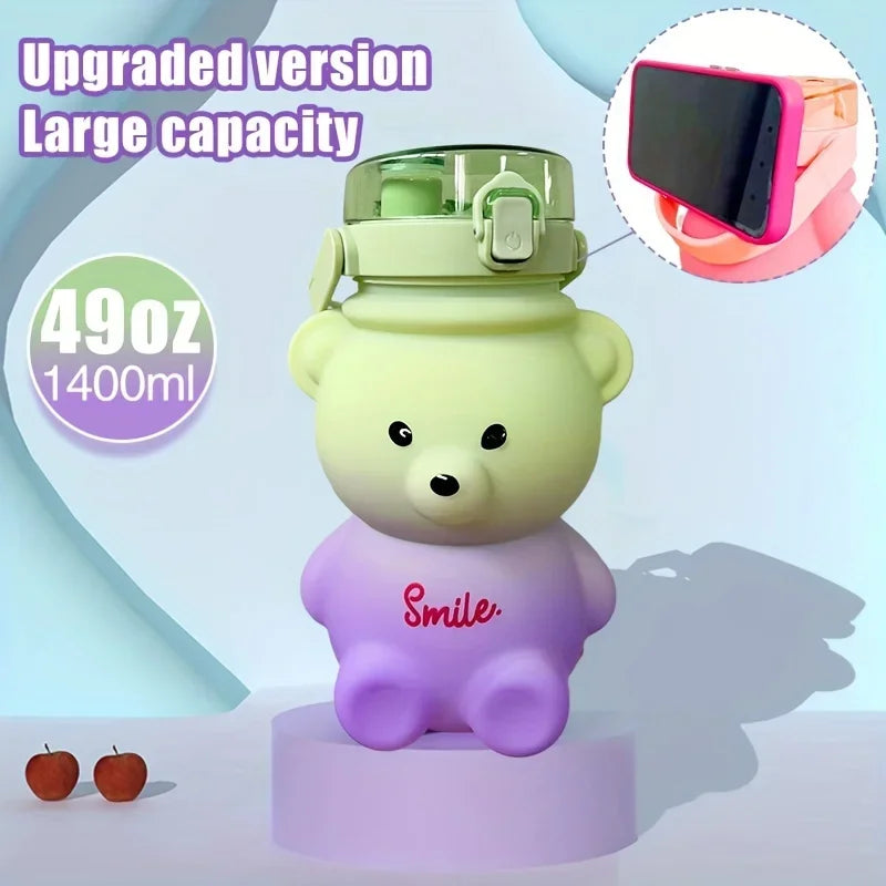 A purple teddy bear shaped water bottle with a green straw and strap is displayed on a stand.