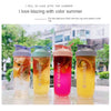 Vier bunte, portable Protein-Shaker-Flaschen mit Saft oder Smoothie im Freien ausgestellt.