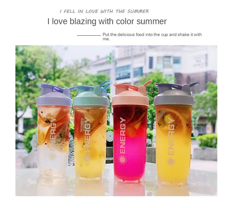 Vier bunte, portable Protein-Shaker-Flaschen mit Saft oder Smoothie im Freien ausgestellt.