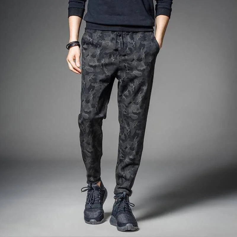 Men's camouflage elastic waist drawstring pants shown on a model standing against a gray background.