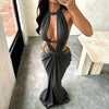 A woman wearing an elegant, draped maxi dress with a deep cut-out back in charcoal gray.