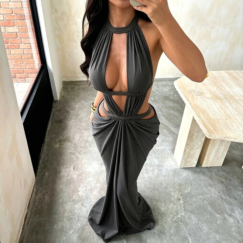 A woman wearing an elegant, draped maxi dress with a deep cut-out back in charcoal gray.