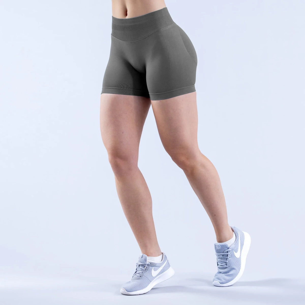 A person is wearing gray seamless high-waisted yoga shorts and white athletic shoes.